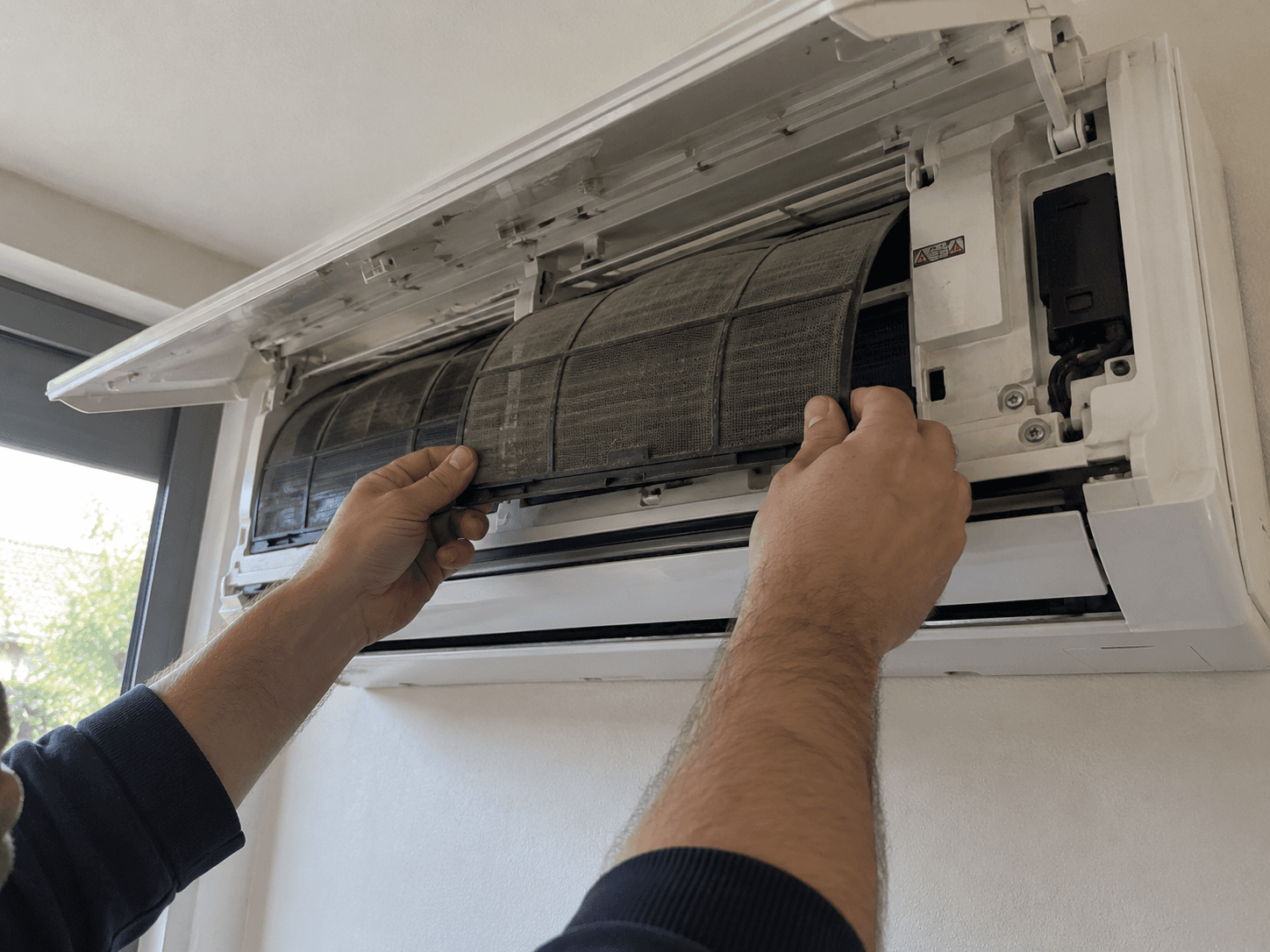 Technicien retirant le filtre d'une climatisation murale